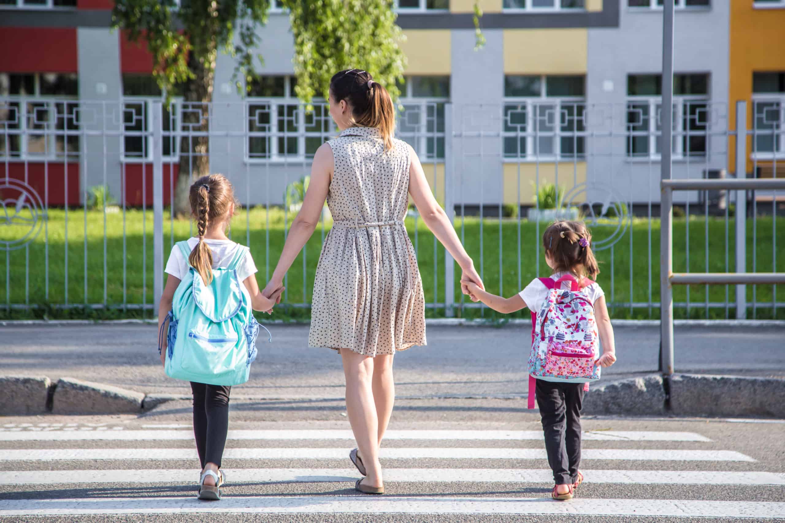 Two girls walking to school with an adult women