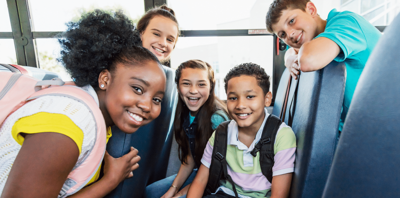 Picture of children smiling together on a bus