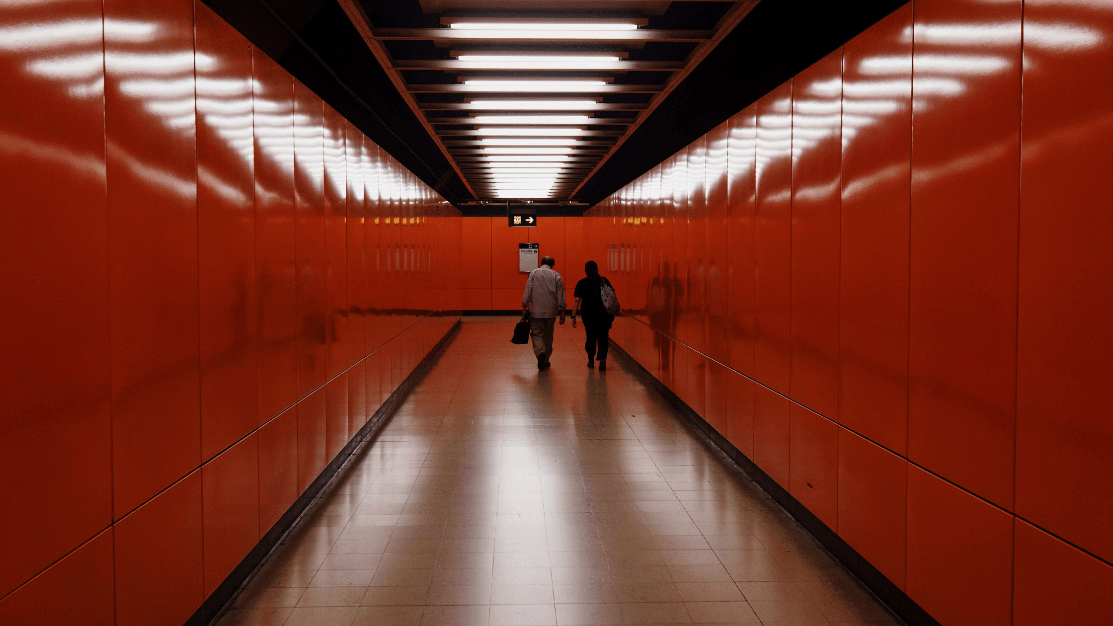 People walking down red hallway